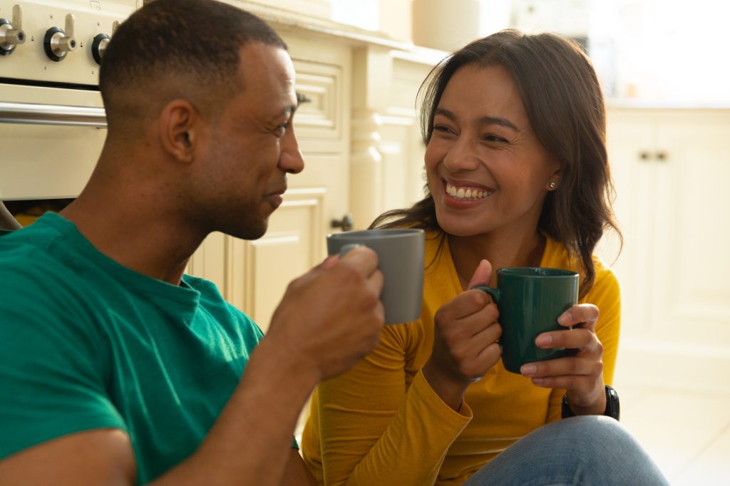 Cheerful young african american couple drinking coffee while spending leisure time together