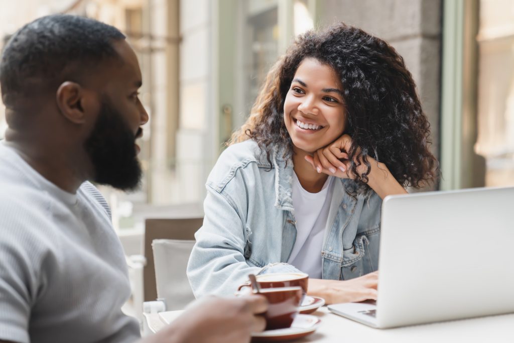 Interested young african-american couple talking communicating together in cafe